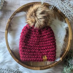 a red knitted hat sitting on top of a wooden bowl next to christmas decorations