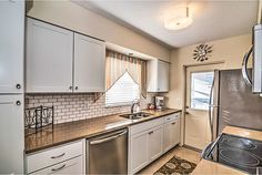 a kitchen with white cabinets and stainless steel appliances, including a dishwasher in the center