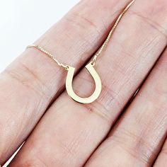 This stunning horseshoe gold necklace is a perfect symbol of good luck and charm. The pendant is crafted from high-quality 14k gold and features a beautifully designed horseshoe with intricate detailing that catches the eye. The pendant hangs on a dainty yet sturdy gold chain that complements the pendant's design, creating an elegant and timeless piece of jewelry. This necklace is perfect for adding a touch of equestrian style to any outfit, and is a must-have for any horse lover, cowgirl, or co Horseshoe-shaped Jewelry With Adjustable Chain, Gold Horseshoe Jewelry With Adjustable Chain, Gold Horseshoe Necklace With Adjustable Chain, Gold Horseshoe Necklace For Good Luck, Everyday Gold Horseshoe Necklace, Horseshoe Necklace With Adjustable Chain As Gift, Horseshoe Necklace With Adjustable Chain For Gift, Horseshoe-shaped Jewelry With Adjustable Chain For Gifts, Horseshoe Jewelry With Adjustable Chain For Gifts