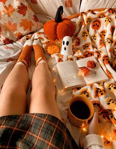 a person is laying in bed with their feet up on the pillow while reading a book and drinking coffee