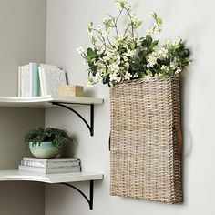 a basket with flowers is hanging on the wall next to some books and other items