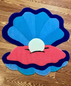 a blue and red rug with a white ball in it's center on a wooden floor