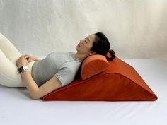 a pregnant woman laying on top of an orange pillow