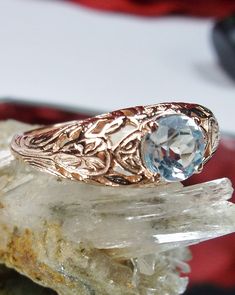 Natural Blue Topaz Ring Description Etched Wedding Design#160 Custom Here we have a Victorian/Edwardian reproduction ring in 14k rose gold with a stunning natural blue topaz gemstone. This full cut round cut genuine blue topaz is 6mm in diameter. The inside of the band is marked 14k for gold. Notice the beautiful floral design of the gold filigree setting. This is a lovely rendition of an Antique filigree wedding ring, and it is made ready to wear. A gift ring box is included and all rings are s Luxury Intricate Design Topaz Wedding Ring, Luxury Vintage Topaz Ring Gift, Luxury Topaz Ring With Intricate Design For Formal Events, Victorian Blue Topaz Ring For Anniversary, Victorian Wedding Birthstone Ring, Antique Blue Topaz Wedding Ring, Antique Blue Topaz Ring For Wedding, Heirloom Blue Topaz Diamond Cut Ring, Heirloom Blue Topaz Ring With Diamond Cut