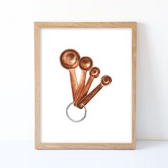 three copper spoons in a wooden frame hanging on a wall next to a white wall