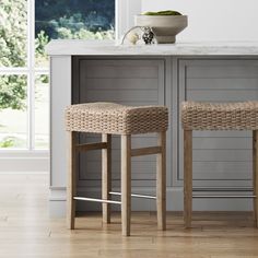 two wicker bar stools sitting in front of a counter