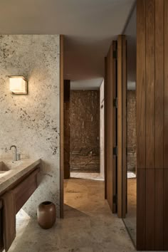 a bathroom with marble walls and flooring next to a wooden sink counter top in front of a mirror