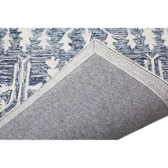 a blue and white area rug with trees on the bottom, in front of a white background