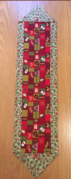 a red and green neck tie on top of a wooden table next to a wood floor