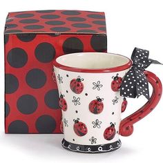 a ladybug coffee mug sits in front of a red box with polka dots