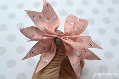 a hand holding a pink bow with white designs on it