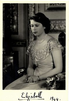 an old black and white photo of a woman sitting at a table with a pen in her hand