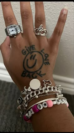 a person's hand with several different rings on it and a ring that has the word love written on it