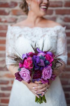 a woman holding a bouquet of purple and pink flowers