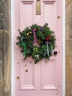 a pink door with a wreath on it and decorations hanging from the front, along with stars