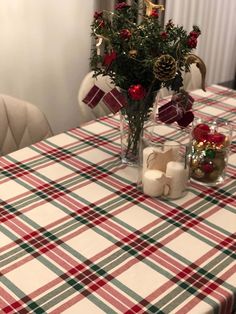 the table is set for christmas dinner with red and green plaid cloth on it,