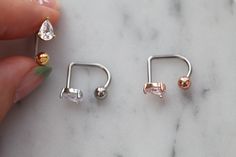 a person is holding three different types of piercings on their fingers and one has a small diamond in the middle