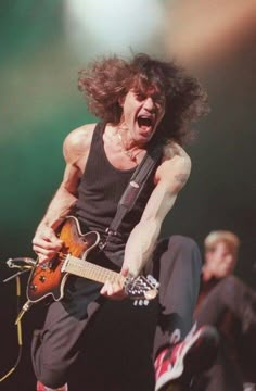 a man with long hair playing an electric guitar