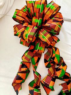 an orange, green and black bow on a white surface