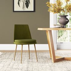 a green chair sitting in front of a table with flowers on it and a vase filled with yellow flowers