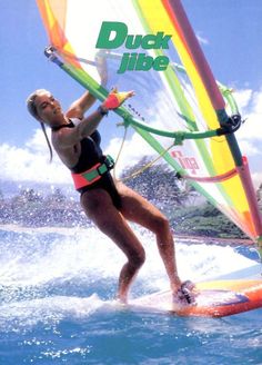 a woman riding on top of a surfboard while holding onto a wind sail in the ocean