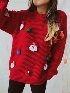 a woman is wearing a red sweater with christmas decorations on it and she has her hands in the air