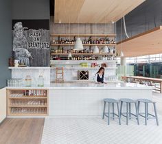 a bar with stools and shelves filled with bottles on the wall next to it