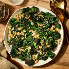 a white plate topped with broccoli and nuts on top of a wooden table