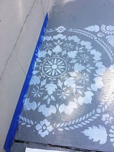 the sidewalk has been painted with white flowers on it and is next to a blue tape