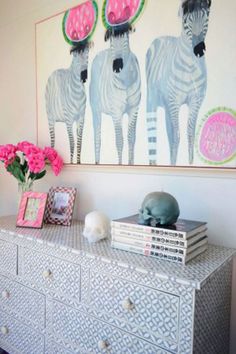 a dresser with two zebras painted on the wall above it and pink flowers in vase