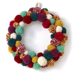 a multicolored pom - pom wreath hanging on a wall