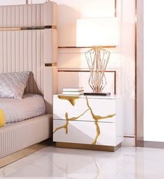 a white and gold nightstand with a lamp on it next to a bed in a room