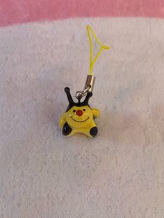 a yellow and black keychain with a smiley face on it's side