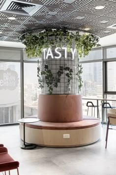 a planter in the middle of a room with chairs around it and a sign that says tasty