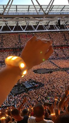 a person holding up their cell phone in front of a large crowd at a concert