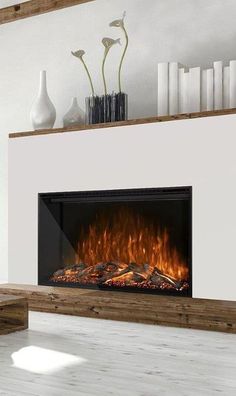 a modern fireplace with white walls and wood flooring in the living room is lit by an electric fire