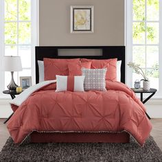 an orange comforter set in a bedroom with pillows and blankets on top of the bed