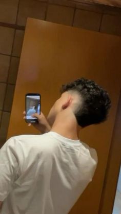 a man taking a selfie with his cell phone in front of him and looking up at the ceiling