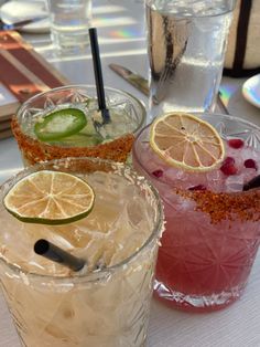 three different types of cocktails on a table with silverware and utensils