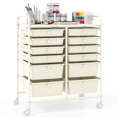 a white cart with lots of drawers and paint on it's sides, next to some markers