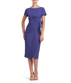 a woman wearing a purple dress and sandals standing in front of a white background with her hands on her hips