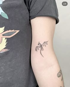 a woman's arm with a small dragon tattoo on the left side of her arm