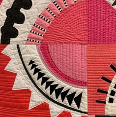 a close up of a pink and black quilt on a table cloth with an abstract design