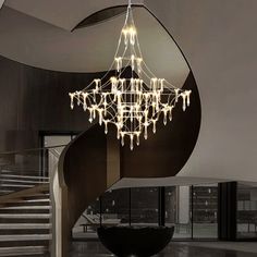 a large chandelier hanging from the ceiling in a room with stairs and windows