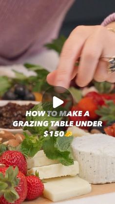 a person cutting up cheese on top of a wooden table with strawberries and other foods