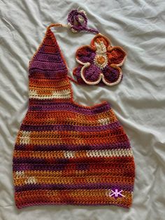 a crocheted purse and hat laying on top of a bed next to a flower