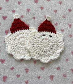 a crocheted santa clause ornament on a pink and white blanket with hearts