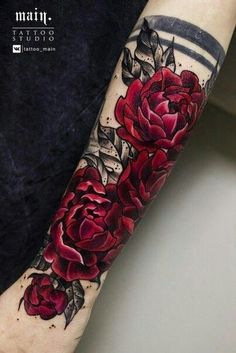 a woman's arm with red roses and leaves tattoo on the left side of her arm