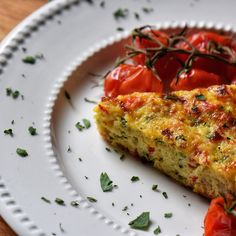 a piece of quiche on a plate with tomatoes