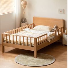 a wooden bed frame in a bedroom with white walls and wood flooring, along with a rug on the floor